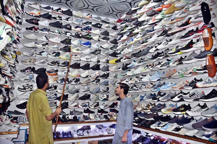 A vendor displaying shoes to attract customers in his shop at Nolakha Landa Bazaar.