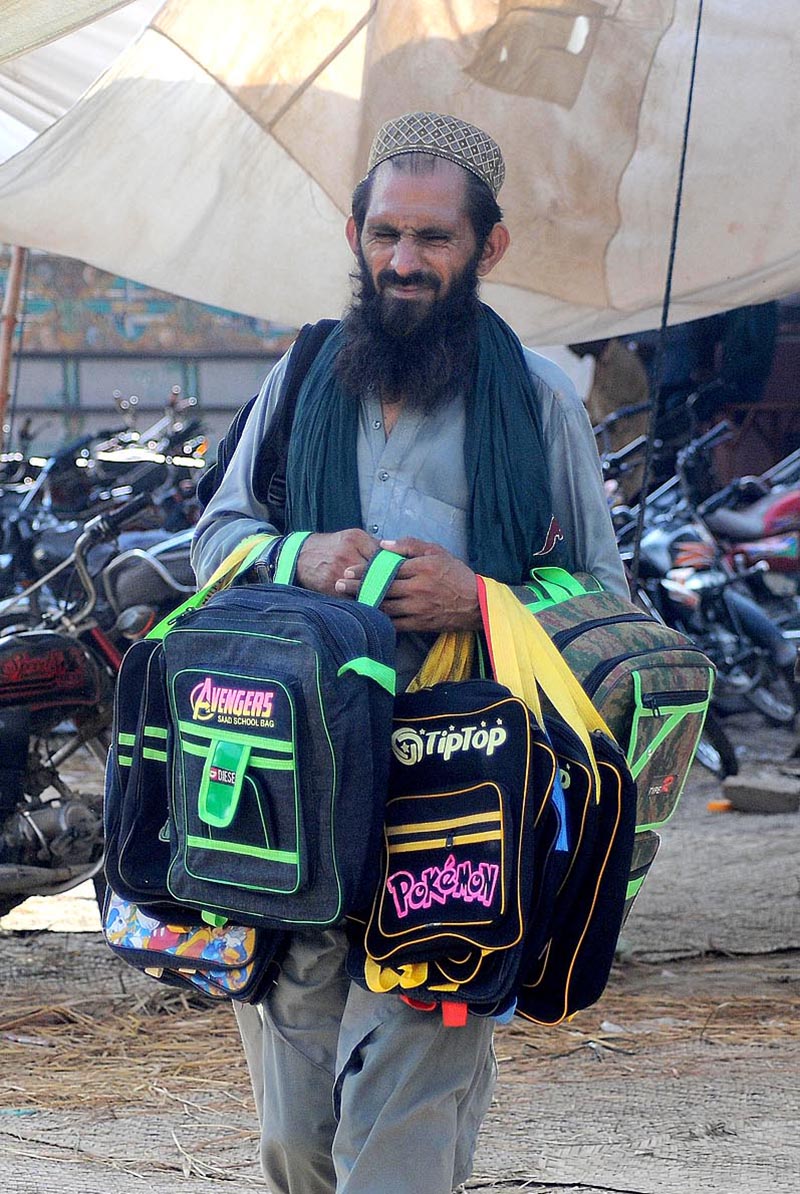 A street vendor selling school bags while shuttling on Khanewal Road