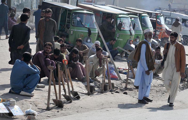 Labourers along with their tools sitting on the roadside waiting for clients to be hired for work at Khanna Pul